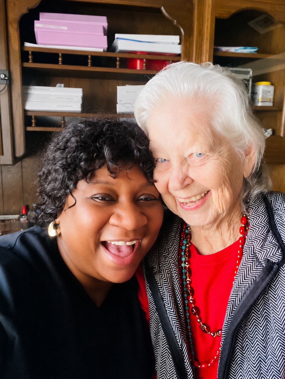 Smiling caregiver supporting happy seniors in a lounge